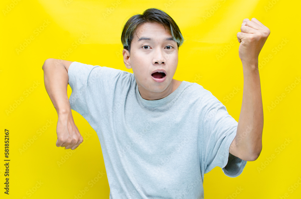portrait of a happy young Asian man raising his hands in celebration of victory while laughing with joy. portrait of a happy young Asian man raising his hands in celebration of victory while laughing with joy.