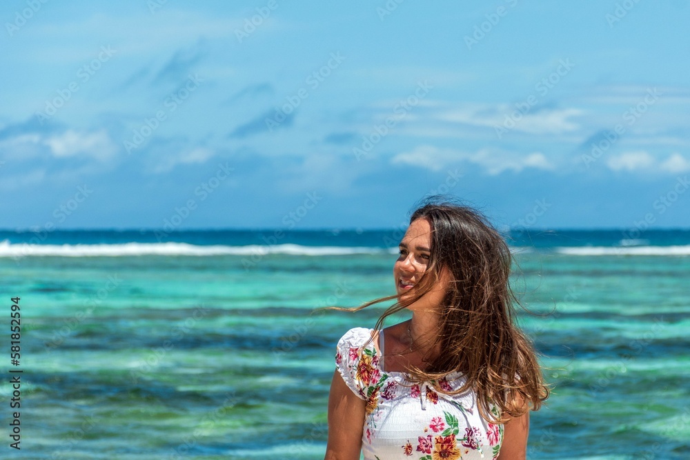 Portrait of beautiful happy woman posing on beach with amazing turquoise ocean in the back Portrait of beautiful happy woman posing on beach with amazing turquoise ocean in the back