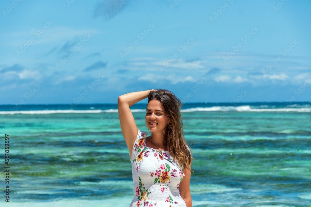 Portrait of beautiful happy woman posing on beach with amazing turquoise ocean in the back
