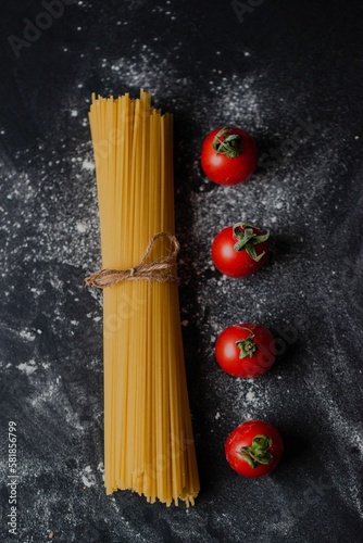 фотографія Closeup of raw pasta on a floury table in a restaurant with cherry tomatoes arou