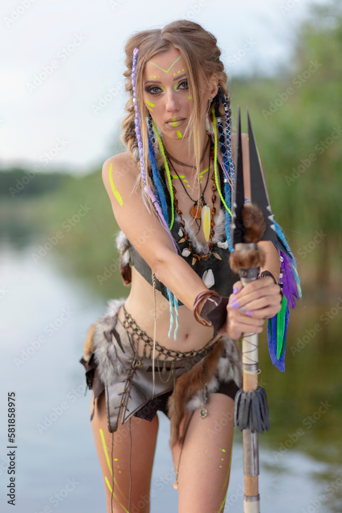 amazon woman in a fur medieval costume with a spear in her hand, in war paint.