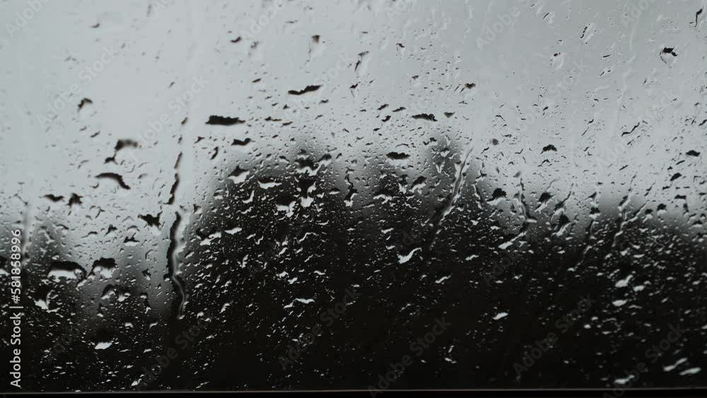 Raindrops dripping on glass window on rainy day. Water drops slide on glass Raindrops dripping on glass window on rainy day. Water drops slide on glass
