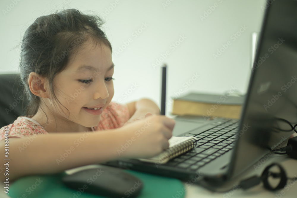 Asian girl watching writing notes and look at laptop at home. Asian girl watching writing notes and look at laptop at home.