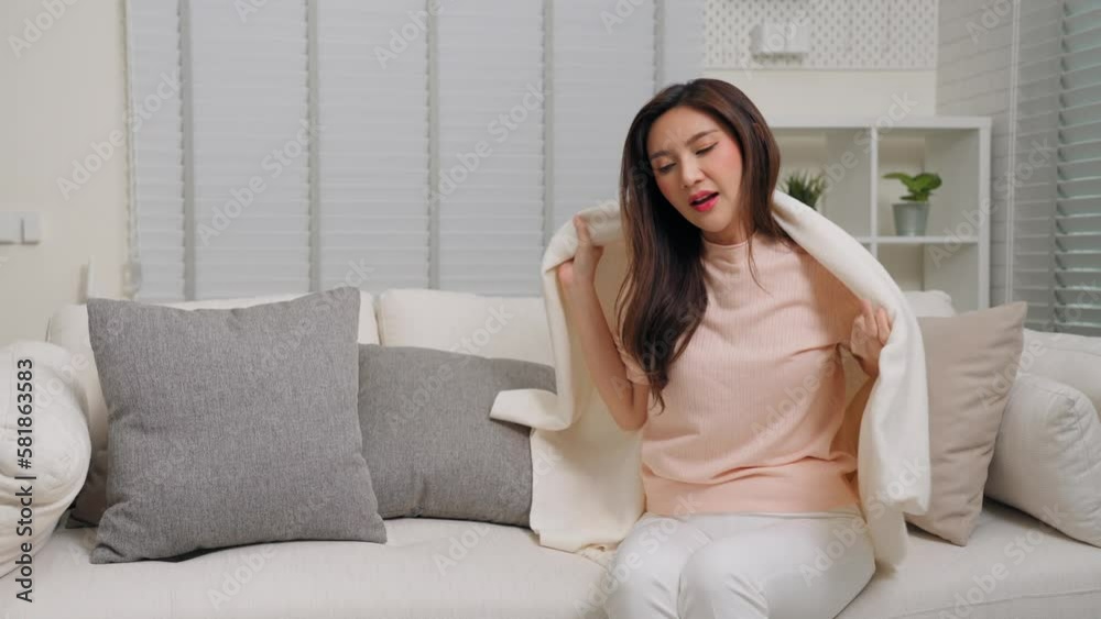Young Asian woman is shivering and covered with a blanket, Ill and flu concept Young Asian woman is shivering and covered with a blanket, Ill and flu concept