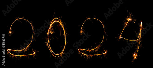 Year 2024 is written in numbers black background with sparklers with sparks.