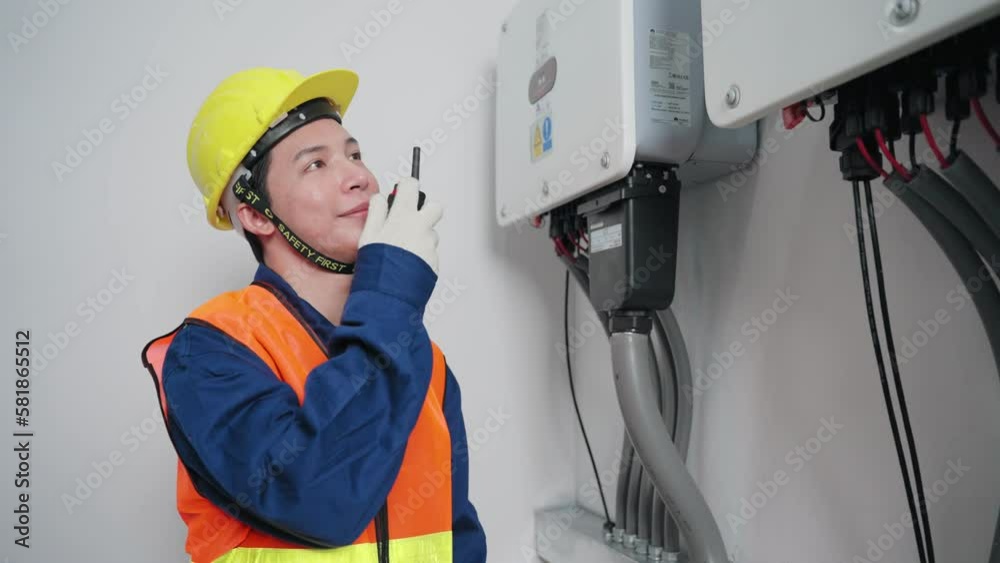 Asian electrical engineer man using walkie talkie checking power distribution cabinet crossed arm and looking at camera with smile in Electrical control room, Maintenance concept