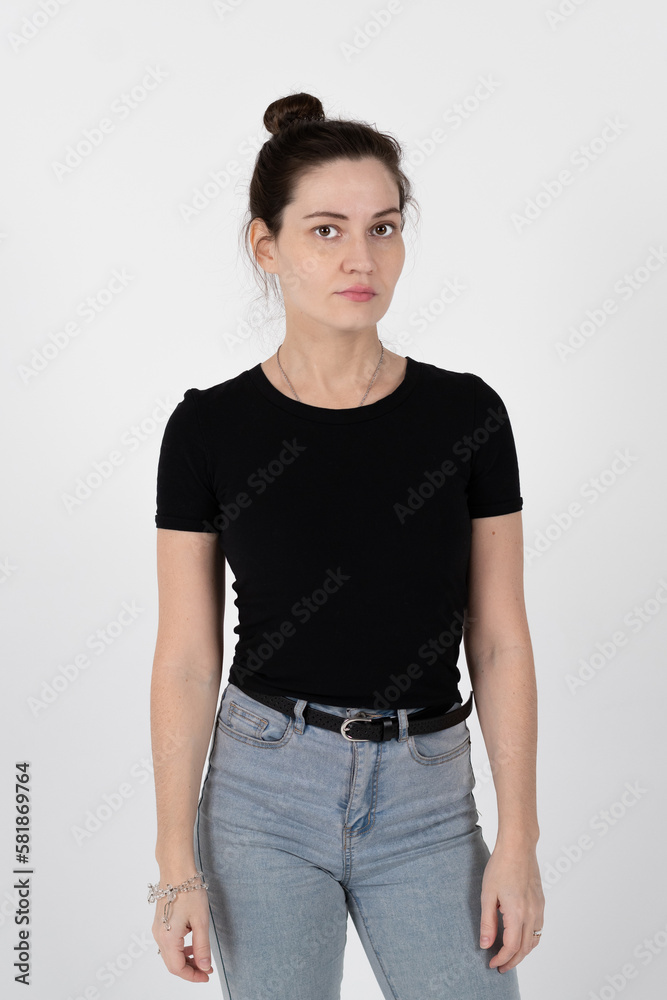A young brunette girl of European appearance in a black T-shirt and blue jeans on a white background A young brunette girl of European appearance in a black T-shirt and blue jeans on a white background