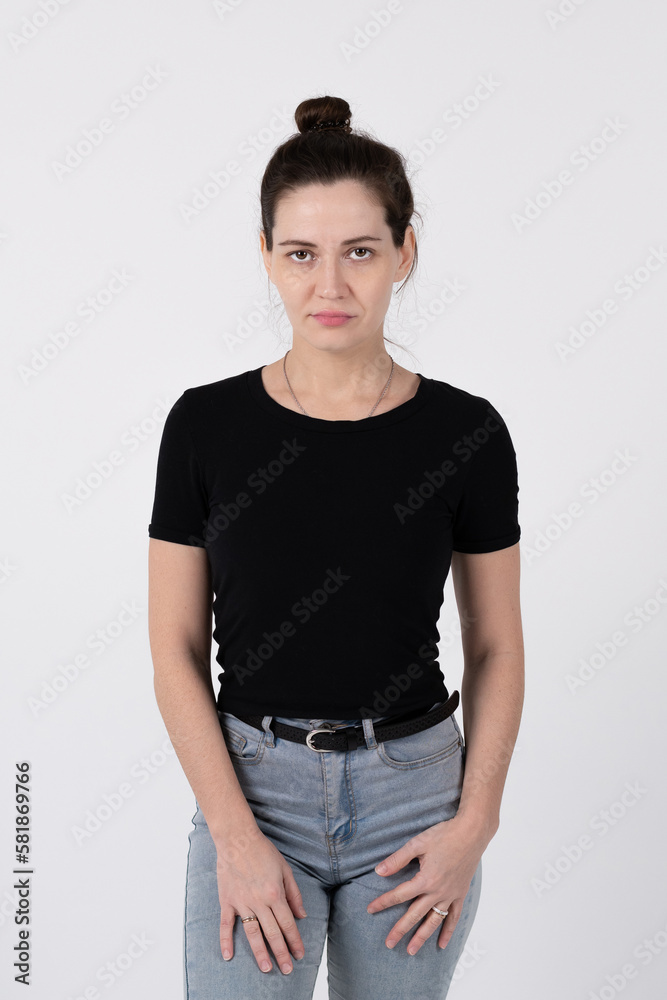 A young brunette girl of European appearance in a black T-shirt and blue jeans on a white background A young brunette girl of European appearance in a black T-shirt and blue jeans on a white background