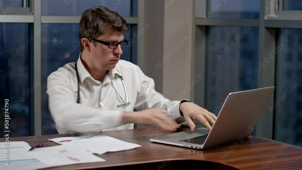 Doctor working late in office on online conference, doing notes on documents. Overworked doctor doing research for the operation. Doctor working late in office on online conference, doing notes on documents. Overworked doctor doing research for the operation.