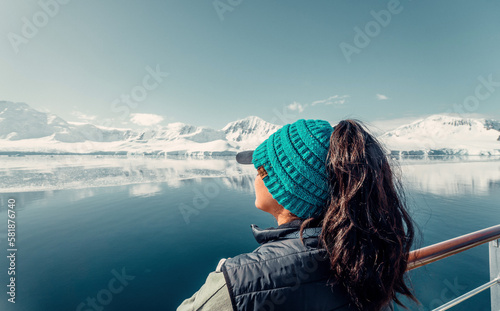 Fototapeta Naklejka Na Ścianę i Meble -  Female Tourist On Luxury Antarctica Cruise Ship Looking Out At The Stunning Scenic Arctic Landscape, Reflection of Mountains 