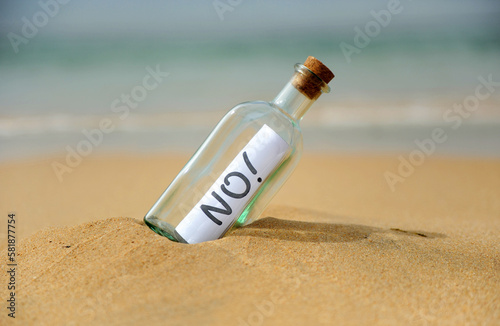 Negative answer, no! Bottle with message on the beach. Bottle with negative answer on the shore
