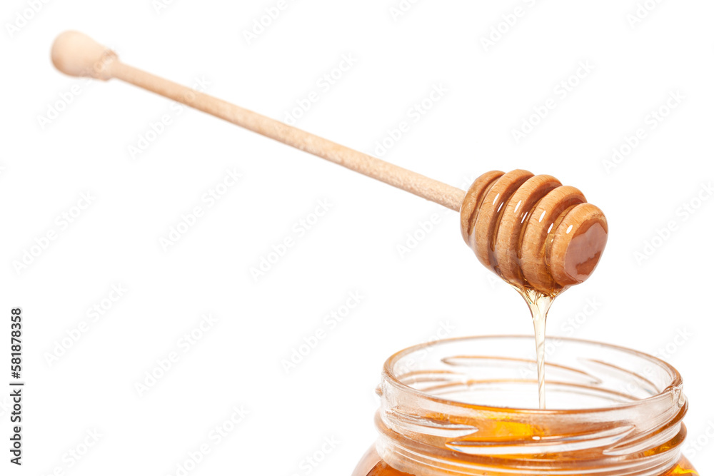 Honey dripping from honey dipper in glass jar. Healthy food concept.