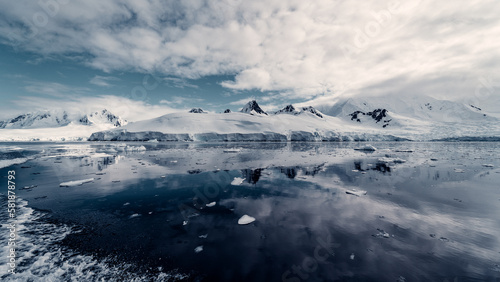 Moody Landscape of Snow Glacier Covered Mountains Reflecting in the Still Arctic Water of Antarctica