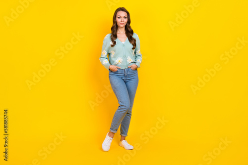 Full length photo of shiny cute lady dressed teal cardigan walking hands arms jeans denim pockets isolated yellow color background