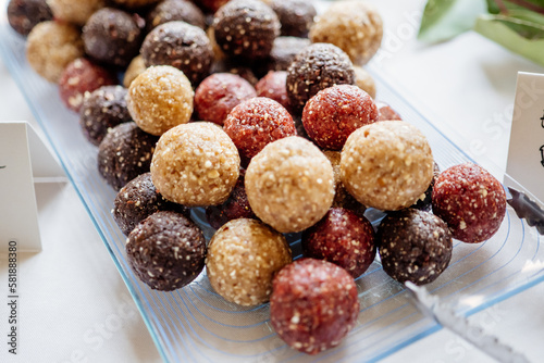 vegane Energyballs und Dattelkugeln in den Geschmacksrichtungen Schokolade, Vanille und Erdbeer als gesunde low-carb alternative zu Süßigkeiten zum naschen in einer Glasschale am Dessert Buffet,
