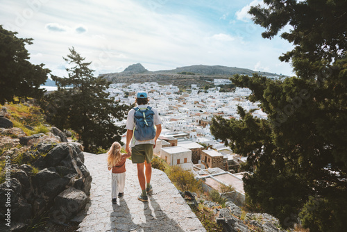 Family travel in Greece father and child sightseeing Rhodes island Lindos city white houses aerial view architecture landmarks summer vacations lifestyle man with daughter walking together photo