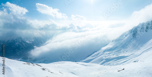 Alpine landscape with peaks covered by snow and clouds. Magical clouds covering peaks of the mountains at the famous St. Anton am Arlberg ski resort.