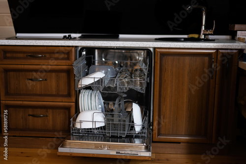 Open dishwasher with clean dishes in wooden surface kitchen.