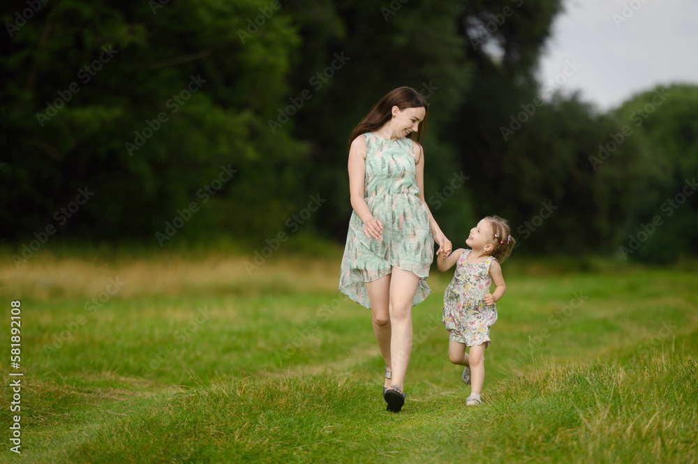 Portraits of joyful mother and daughter spend time together, enjoy happy family time, run in the park. The concept of a happy family, family day,mother's day, countryside vacation, unity with nature.