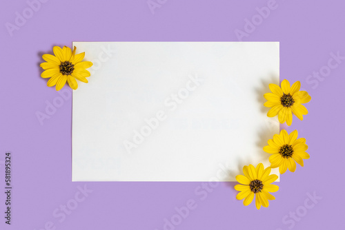 Blank notebook paper and spring flowers on purple background. Free space for text.
