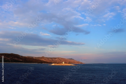 Small lighthouse illuminated by warm sunset light  near island Hvar  Croatia. 