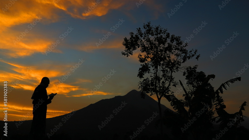Fototapeta premium Silhouettes of people reading the Qur'an against the background of Mount Merbabu