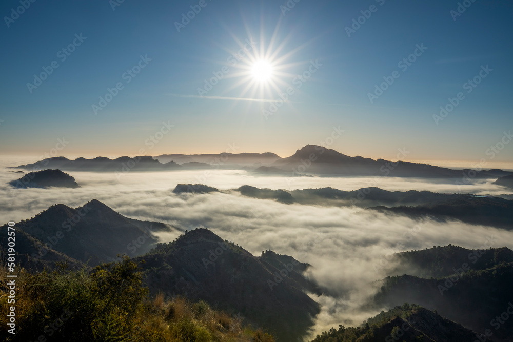 Scenic view of a mountainous landscape with low clouds or mist and the morning sun illuminating the scene