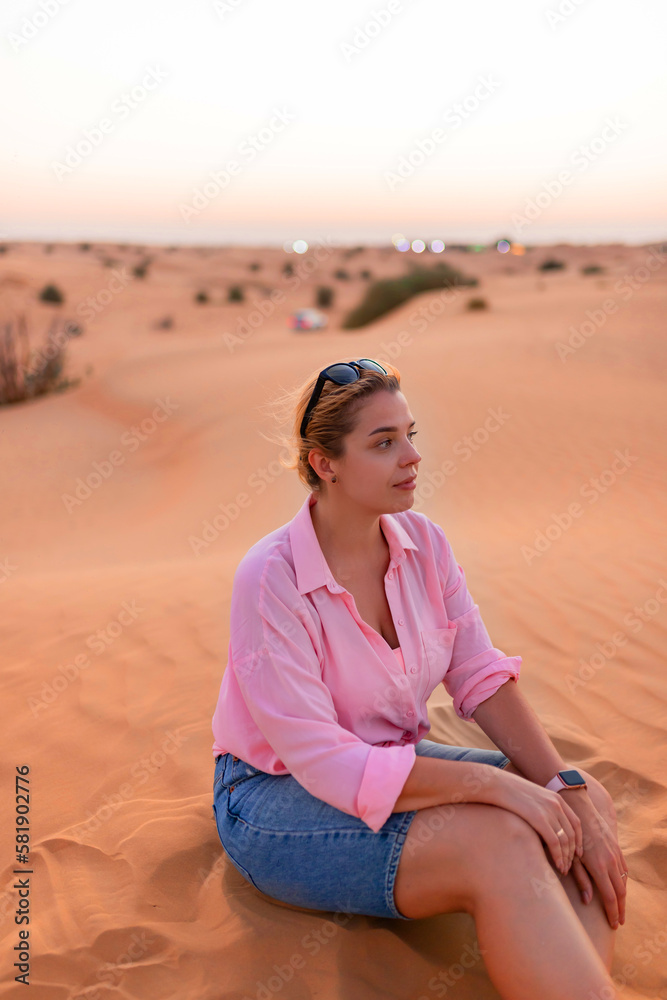 European attractive woman sitting on the crest of a dune in desert