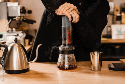 Aeropress coffee. Barista is pushing aeropress for pouring coffee drops trought aeropress to pot. Alternative scandinavian coffee brewing method.