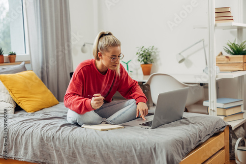 A female college student is studying for the exam and doing some research on laptop