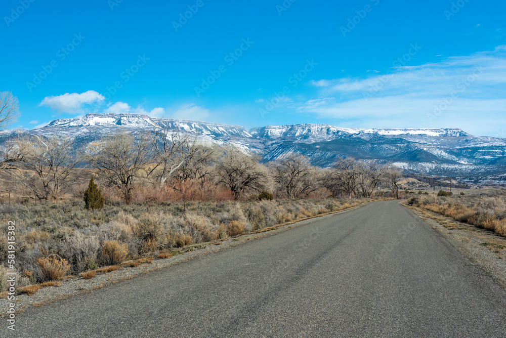 Naklejka premium Road on Reeder Mesa in the Grand Valley, Colorado, heading toward the snowy Grand Mesa in winter 