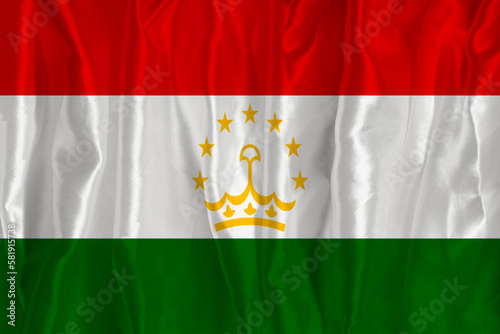 The flag of Tajikistan on a silk background is a great national symbol. Texture of fabrics The official state symbol of the country