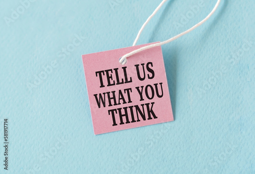 Tell Us What You Think text quote on a pink card, Business Concept on Blue Background.