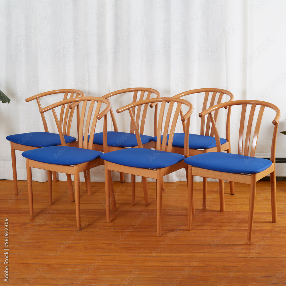 Set of Mid-century modern minimalist wooden chairs with a blue seats. 1960s wishbone-style chairs. Front view in front of long white curtain. 