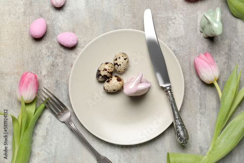 Table setting with Easter eggs and tulips on grunge background