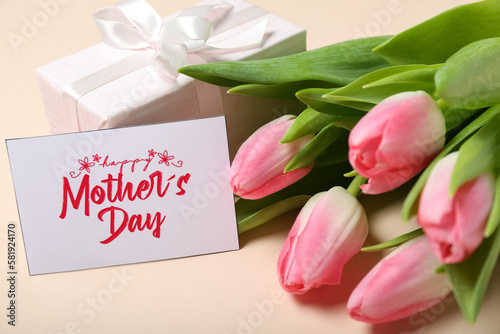 Greeting card with text HAPPY MOTHER'S DAY, gift box and beautiful tulip flowers on pink background