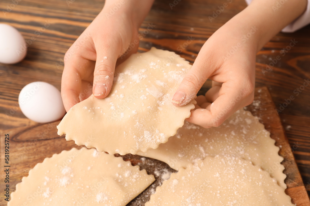 Female hands with raw meat empanadas on wooden background, closeup Female hands with raw meat empanadas on wooden background, closeup