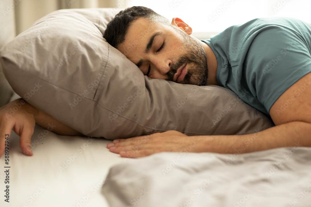 Portrait of peaceful european man sleeping in bed at home, lying with
