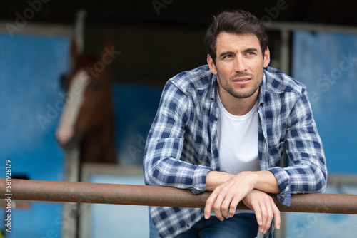 Fototapet contemplative man at riding stables