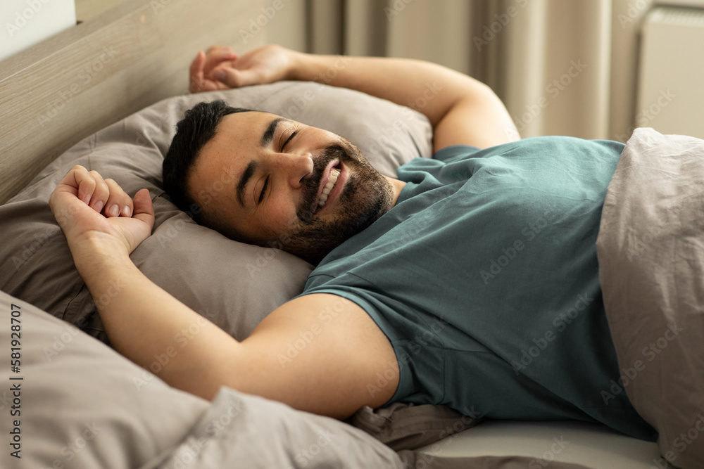 Happy relaxed man lying in comfy bed, enjoying good morning in bedroom,  stretching his body after waking up Stock Photo | Adobe Stock