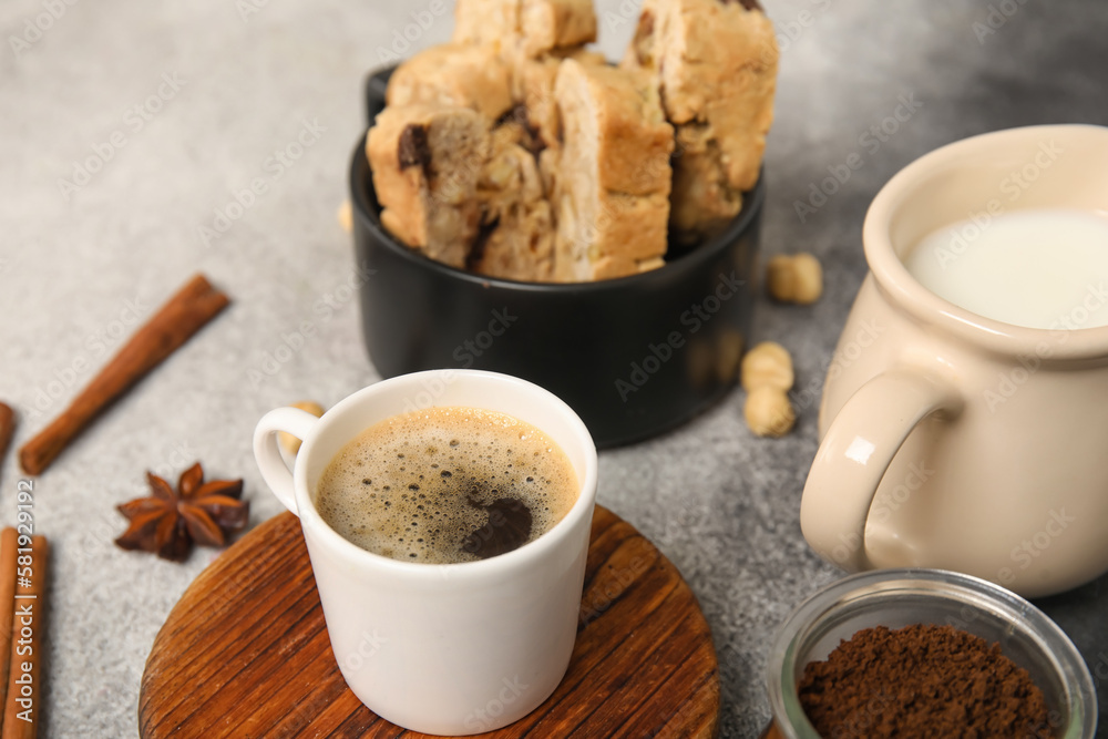 Delicious biscotti cookies, pitcher with milk and cup of coffee on grey grunge background