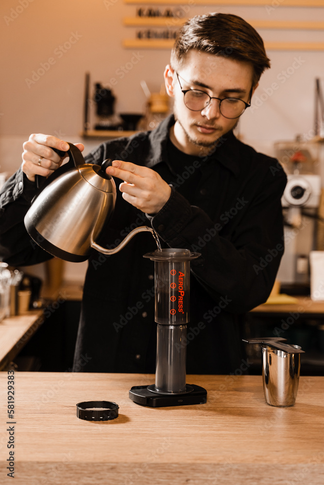Barista is brewing aeropress coffee in cafe. Process of aeropress alternative method brewing coffee. Pouring hot water over roasted and ground coffee beans in aeropress. Barista is brewing aeropress coffee in cafe. Process of aeropress alternative method brewing coffee. Pouring hot water over roasted and ground coffee beans in aeropress.