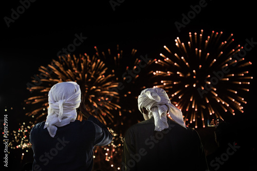two Arab men watching fireworks in the night sky