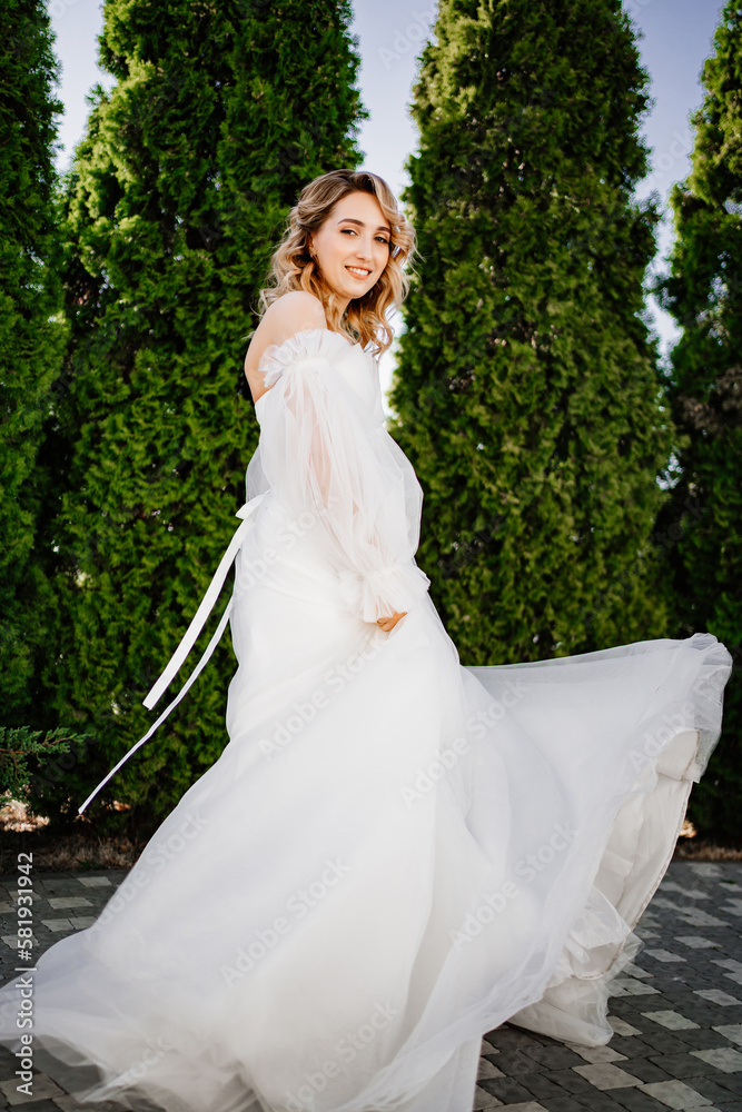 beautiful bride in a white delicate dress dances and spins in the park. 