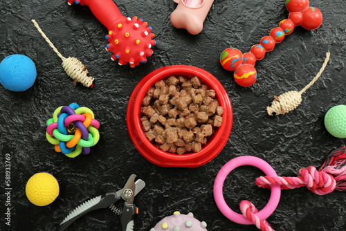 Composition with bowl of wet food and pet care accessories on dark background