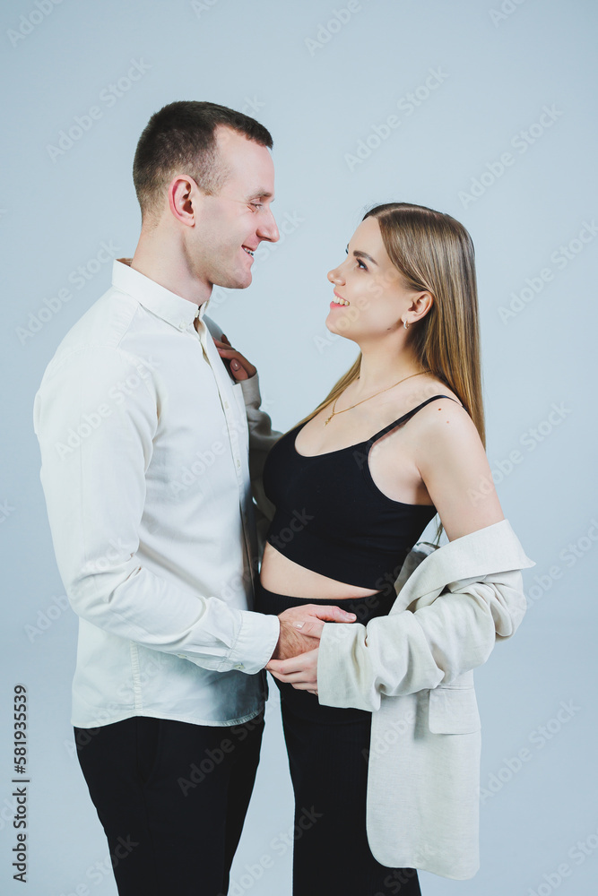 Beautiful young couple in love hugging on a white background. A stylish couple embraces and enjoys feelings. Men and women in stylish casual clothes Beautiful young couple in love hugging on a white background. A stylish couple embraces and enjoys feelings. Men and women in stylish casual clothes