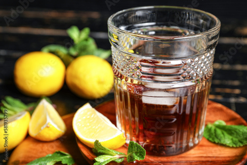 Glass of rum with lime on dark wooden background, closeup