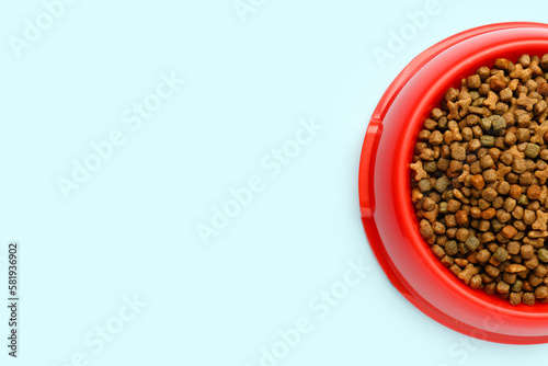 Red bowl of dry pet food on color background