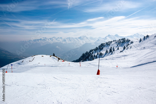 Ski slope with snowy mountains and valley in winter in Austrian Alps. Blue sky with mountains.