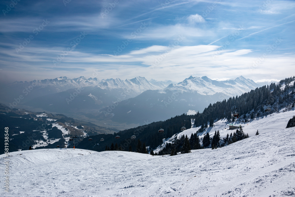 Snowy mountain peaks with a deep valley and a chairlift in the Austrian Alps.